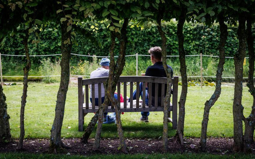 Two people sat on a bench in David Austin's garden.