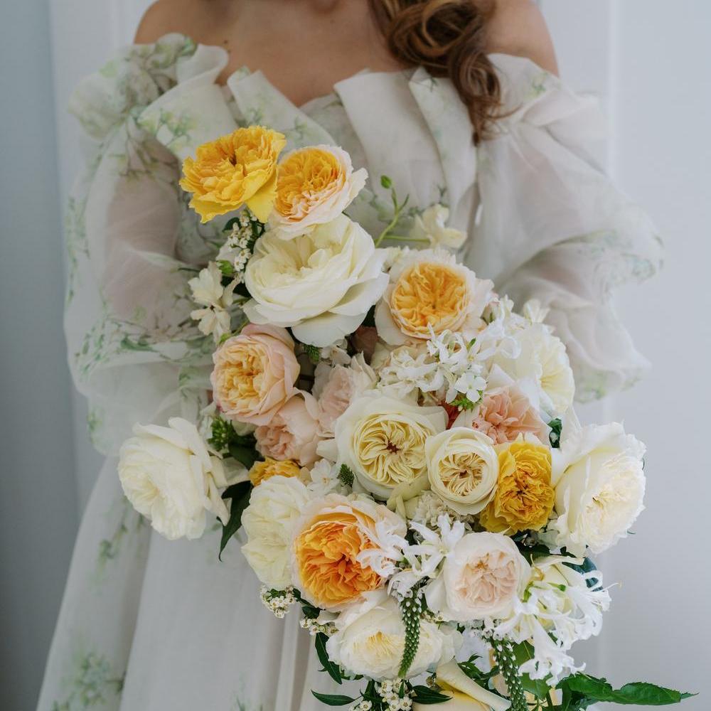 A display of David Austin wedding roses as a bouquet being held by a woman